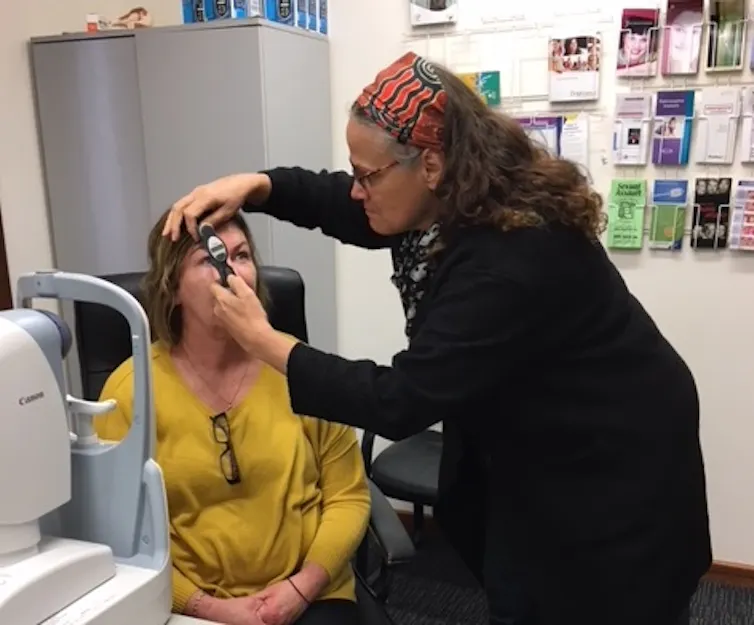 woman checks eyes of a second woman