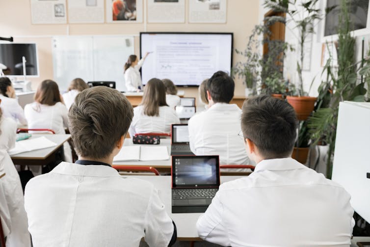 Students face the whiteboard in a classroom.