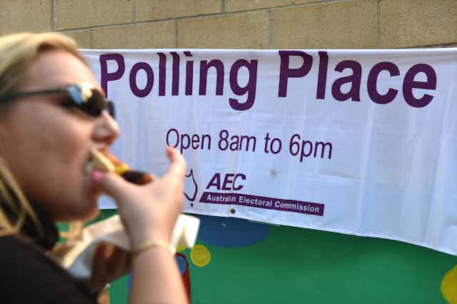 Woman eats a sausage sandwich outside polling booth