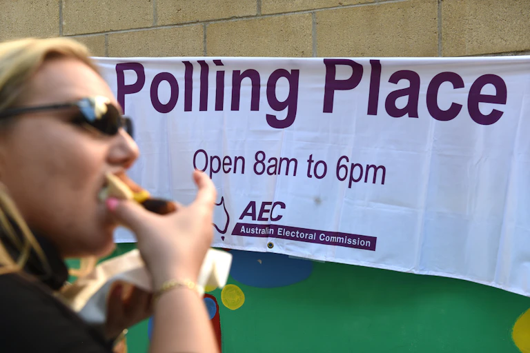 Woman eats a sausage sandwich outside polling booth