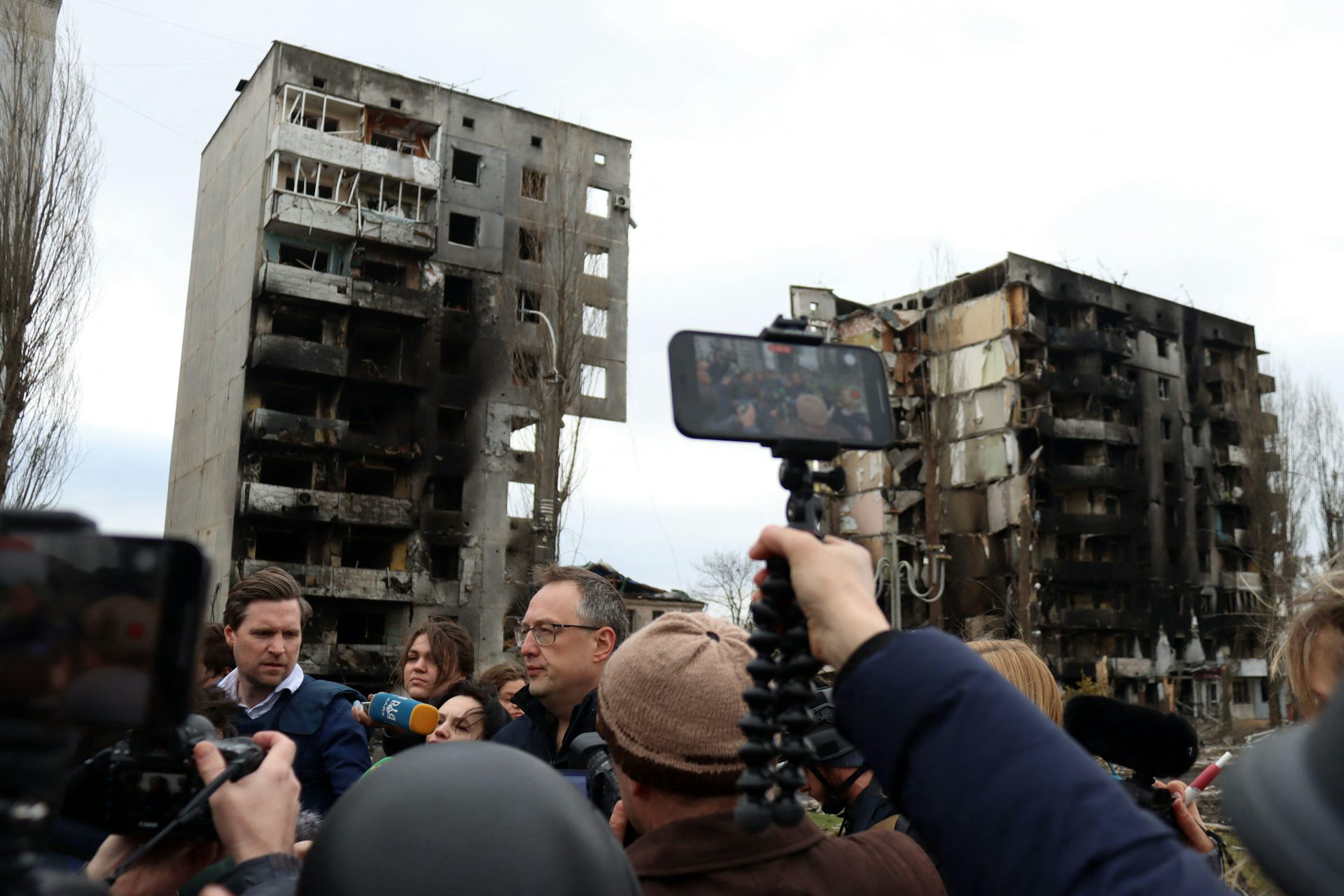 A reporter holds up a mobile phone to film a Ukrainian government press briefing in the town of Borodyanka, north of Kyiv, April  2022.