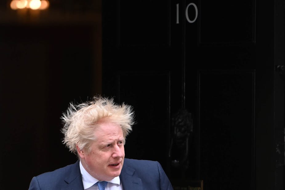 Boris Johnson walking out of 10 Downing Street, the wind is blowing his hair 