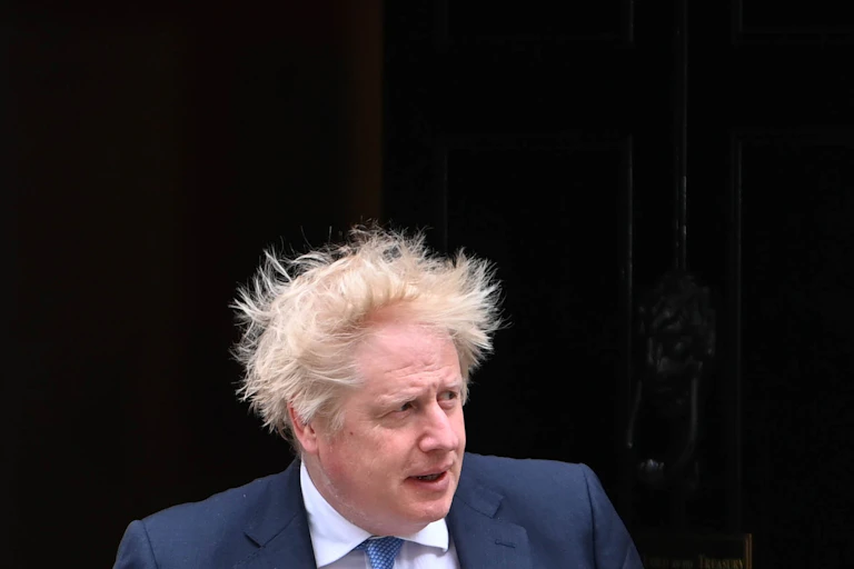 Boris Johnson walking out of 10 Downing Street, the wind is blowing his hair