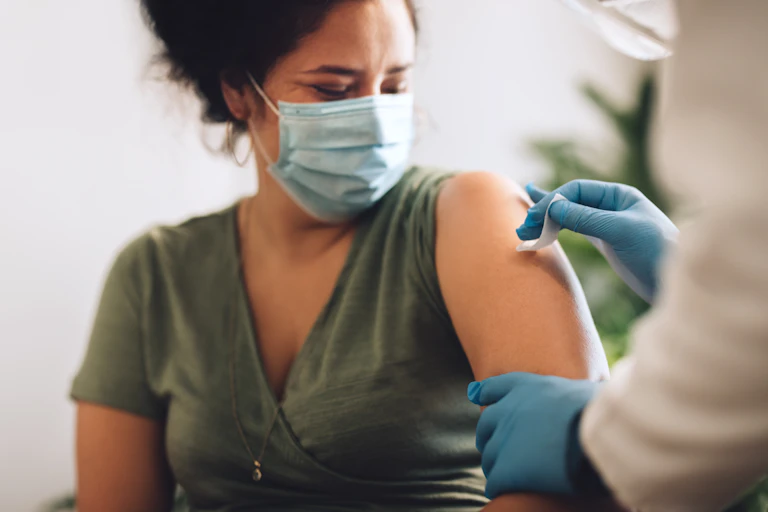 A woman has her upper arm prepared to receive the COVID-19 vaccine.