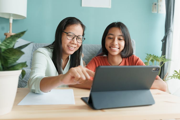 a mother and daughter sit in front of a tablet