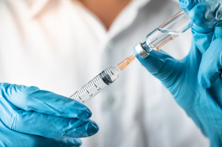 A healthcare worker draws up a vial of vaccine.