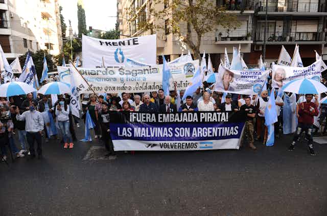 March in Buenos Aires for the 40th anniversary of the Falklands War, marchers hold up a sign sying 'The Malvinas are Argentinian'