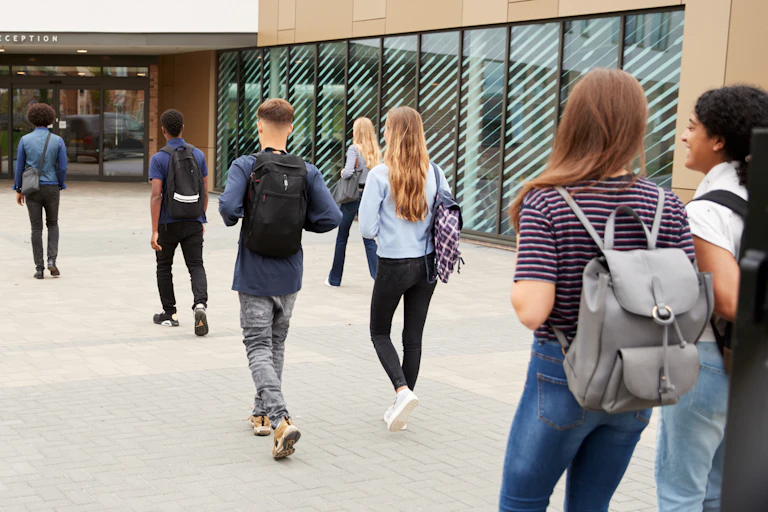 Students seen walking outdoors with backpacks.