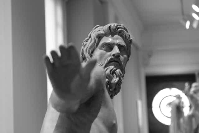 A statue pictured in black and white, its hand is blurred in the centre of the photo