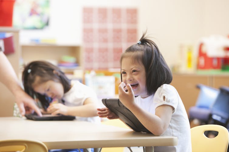 A student of color with down syndrome uses a tablet in the classroom.