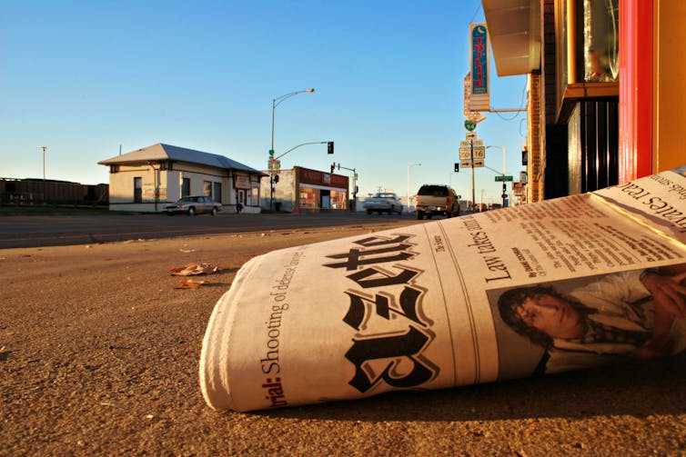 Newspaper lying on ground in country town.