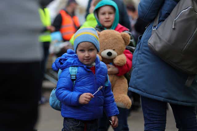 Child Ukraine refugees holding teddy bear