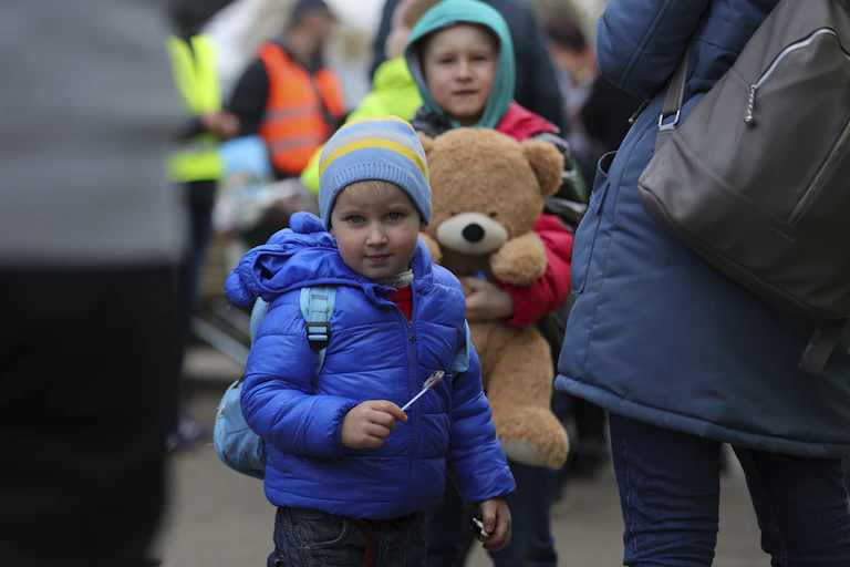 Child Ukraine refugees holding teddy bear