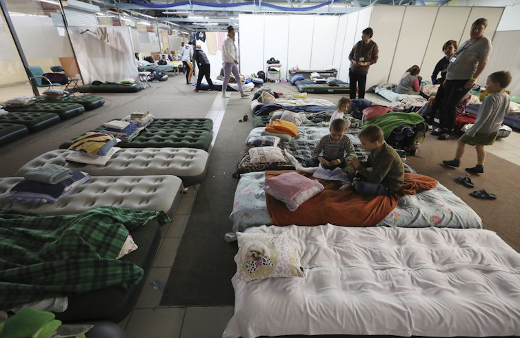 Ukraine refugees play on mattresses at temporary shelter