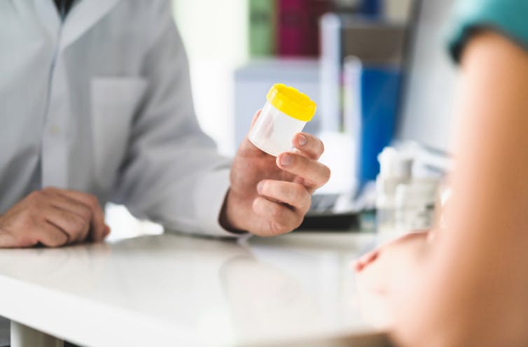 A doctor holding a urine sample jar.