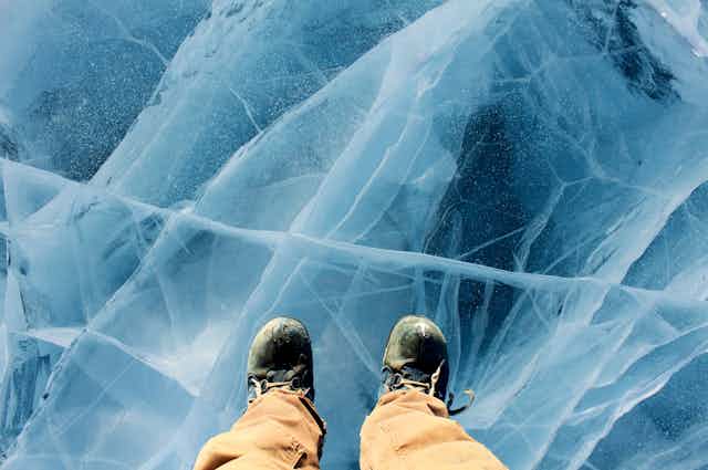 Feet in boots stand on a layered ice sheet