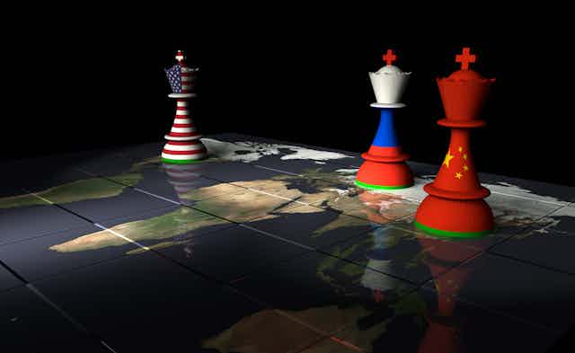 A U.S. flag chess piece on a map across from Russian and Chinese chess pieces.