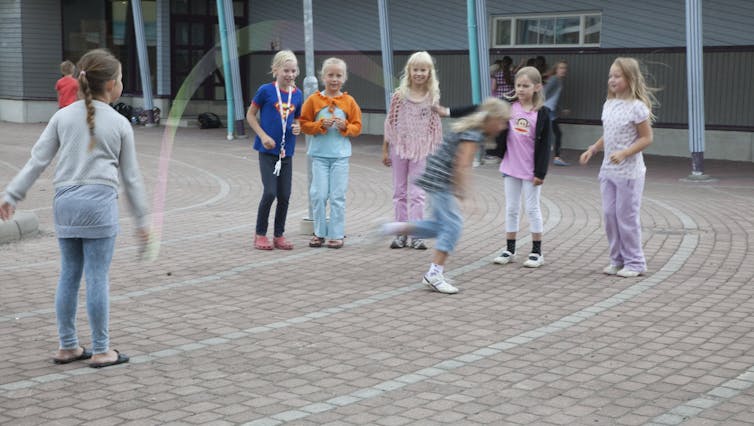 Young girls play outside together, jumping rope, in Turku, Finland