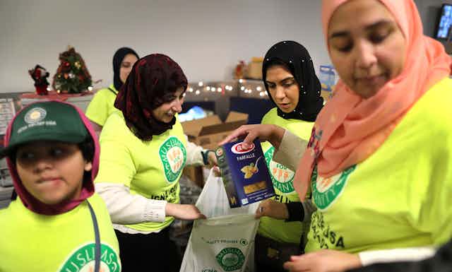 Muslim volunteers assemble bags of food to give away.