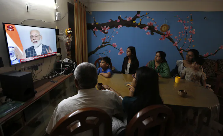 A family watches a television showing Indian Prime Minister Narendra Modi.