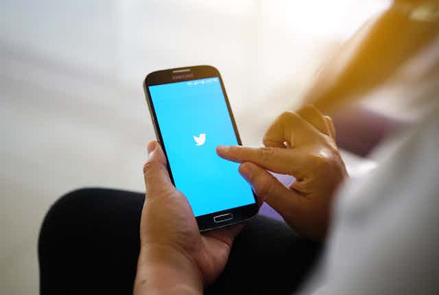 Hands holding phone with Twitter logo