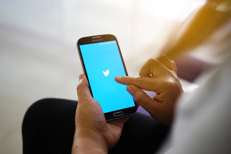 Hands holding phone with Twitter logo