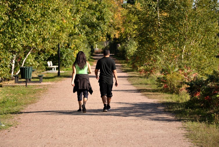 Un jeune couple font une marche dans un parc pendant une journée ensoleillée