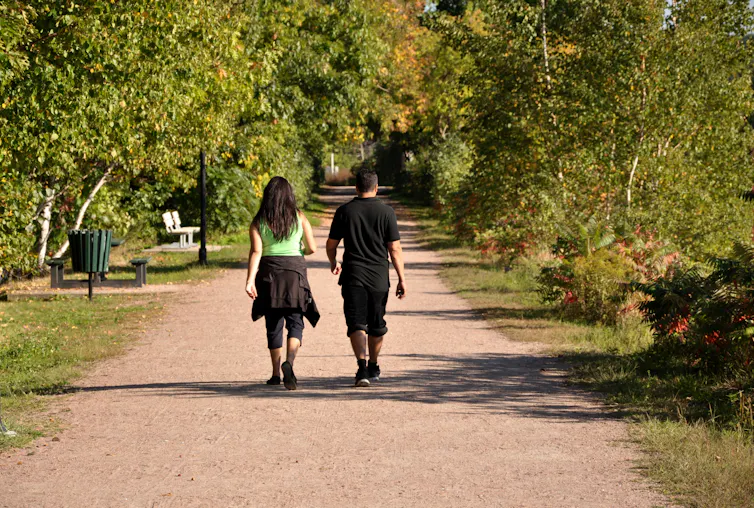 Young adult man and woman go for a brisk walk in the park on a sunny day.