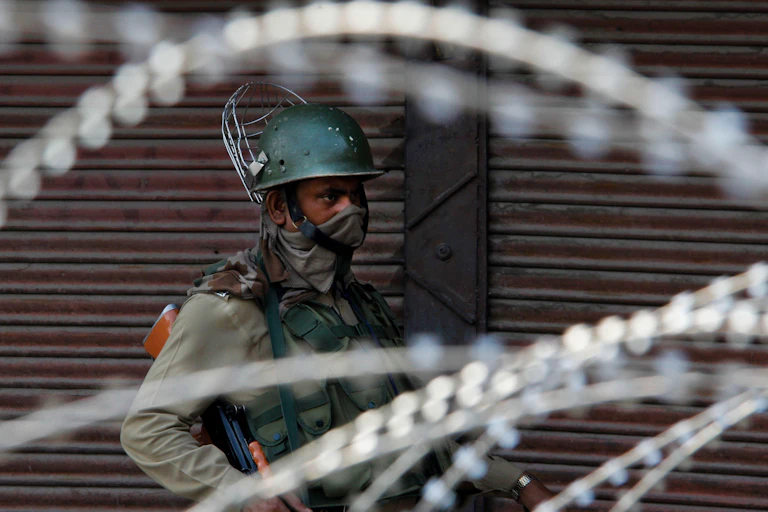 A soldier wearing a green helmet and carrying a gun.