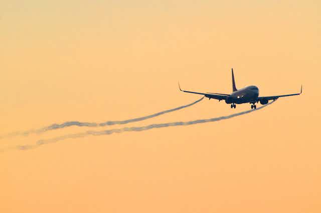 Avión comercial volando con estelas de humo
