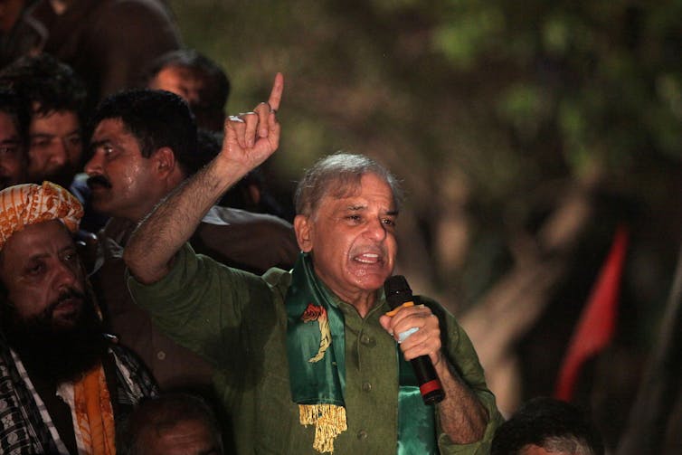 A man wearing a green suit with his arm in the air.