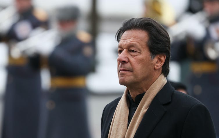 A man wearing a pink scarf and dark clothes.