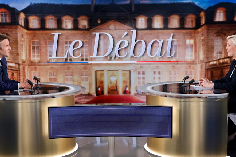 Emmanuel Macron and Marine Le Pen sitting across from one another during a TV debate.