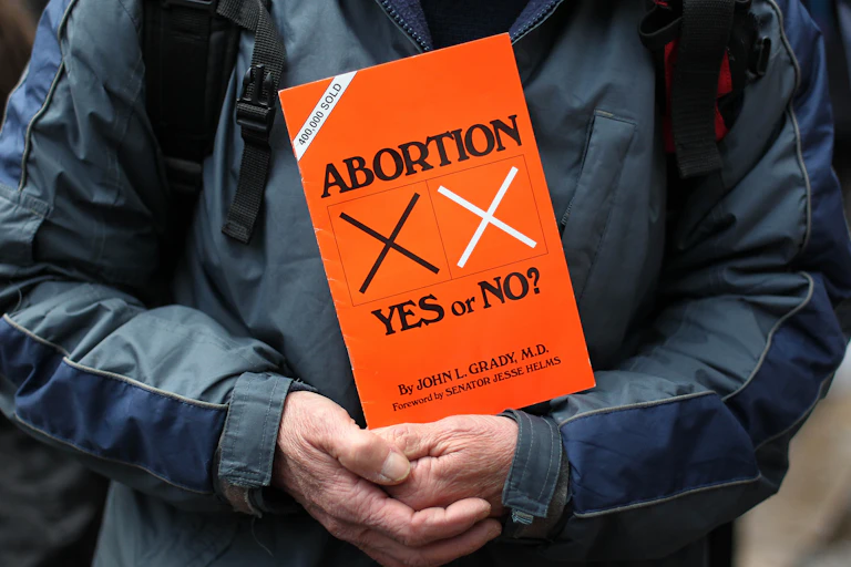 An orange placard saying 'Abortion: Yes or No.'