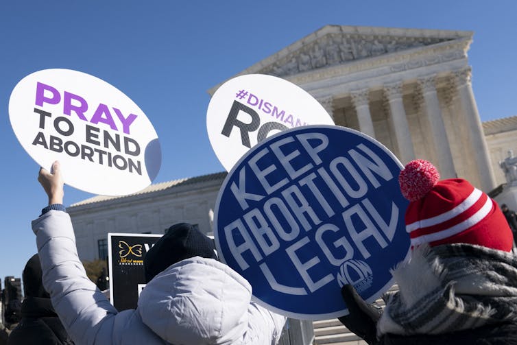 People holding placards that say 'pray to end abortion,' and 'keep abortion legal.'