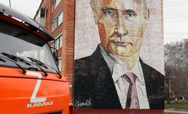 A truck marked with the letter 'Z' drives past a building with a mural depicting Vladimir Putin,  in the Russian town of Kashira.