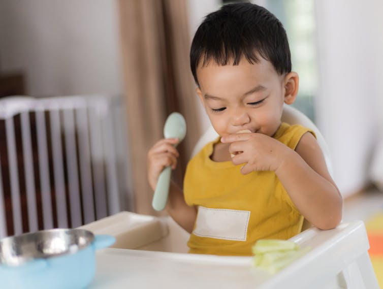 a child seen picking up a spoon.