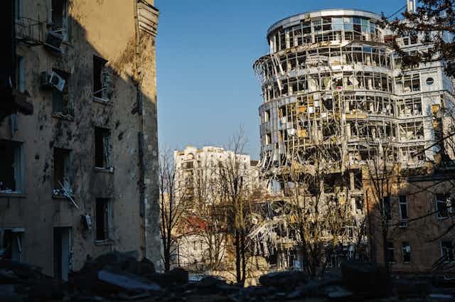 Ruins of a modern metal and glass building that was destroyed by bombardments, as well as an older building.