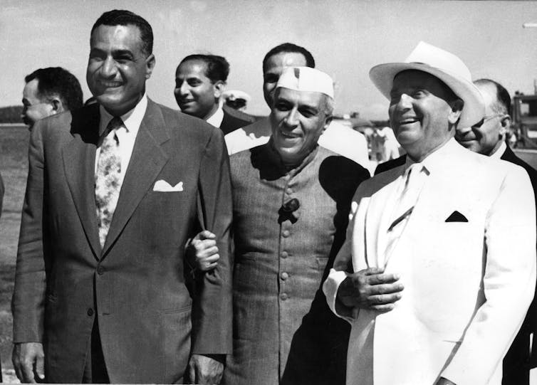 Yugoslav President Josip Broz Tito, Egyptian President Gamal Abdel Nasser and Indian Prime Minister Jawaharlal Nehru link arms in the sunshine.