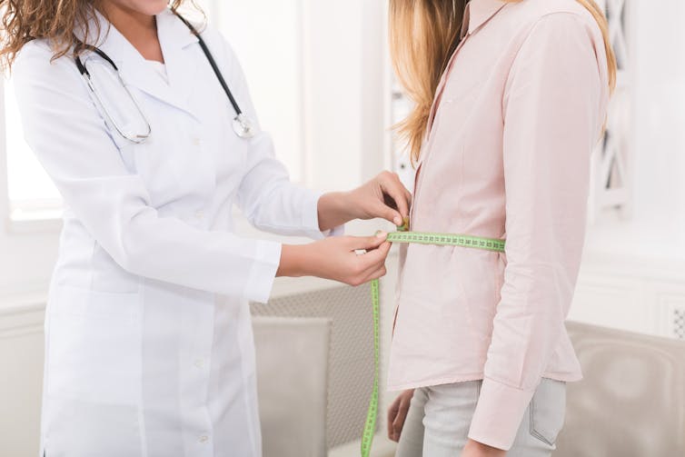 Doctor measuring woman's waist