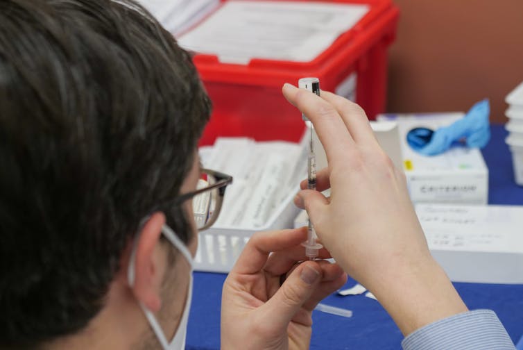pharmacist prepares covid vax shot
