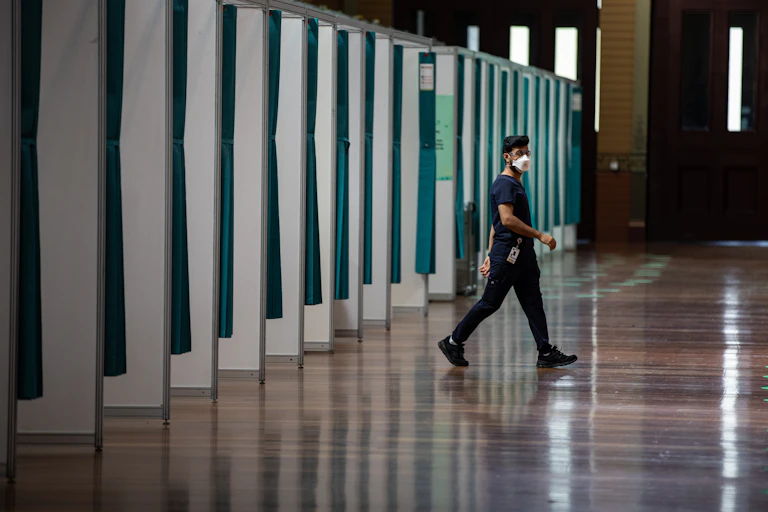 nurse walks near vaccination cubicles