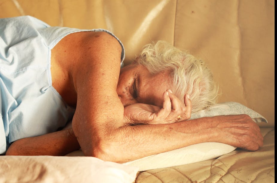 An elderly woman sleeps in bed.