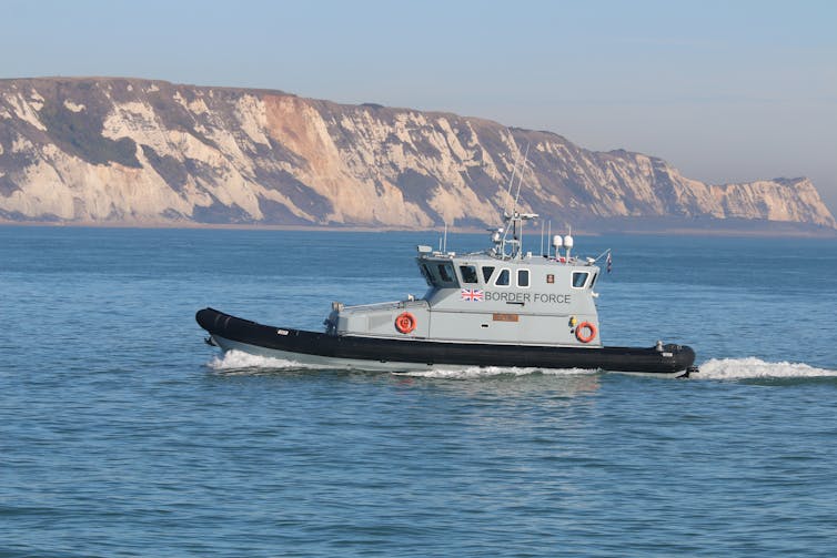 A Border Force boat pictured returning to Folkestone Harbour, with white cliffs in the background.