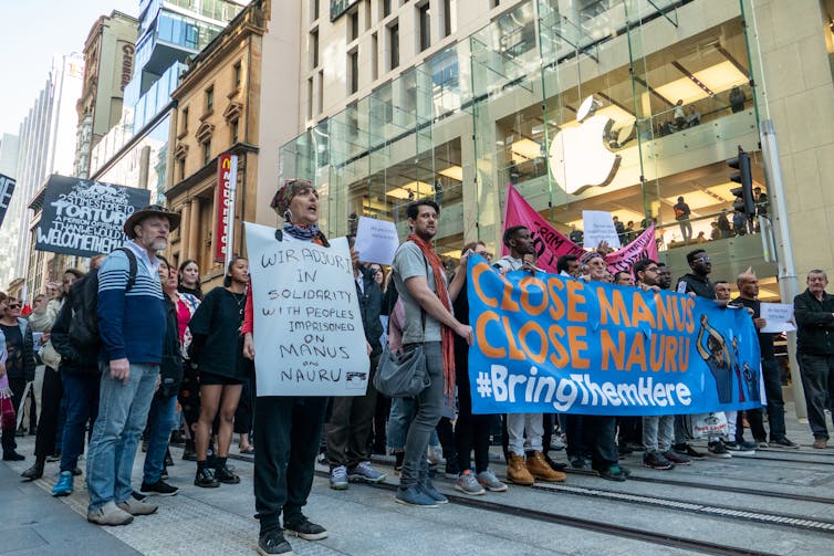 Protestors in Australia hold up signs decrying the government's detention of refugees offshore.