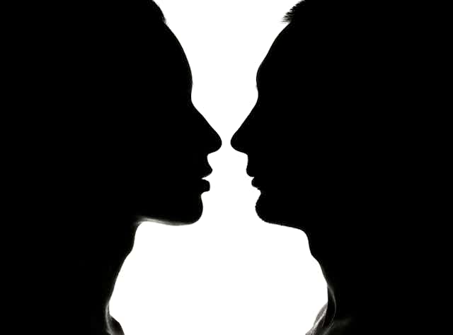 Siluetas enfrentadas de perfil de hombre y mujer en negro sobre blanco.