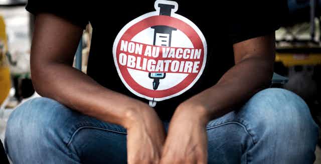 Gros plan sur le T-shirt d'un jeune homme indiquant Non au vaccin obligatoire