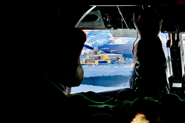 View of white industrial buildings in a snowy landscape seen from the interior of a plane