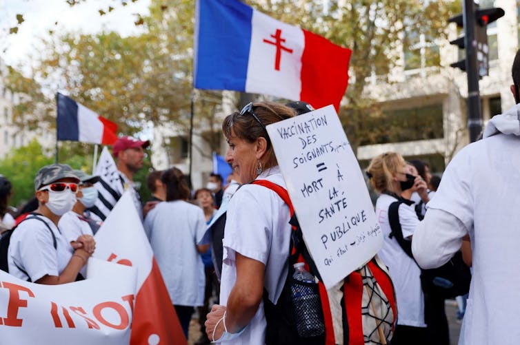 Défilé de soignants en blouse blanche et panneau « Vaccination des soignants = mort à la santé publique »
