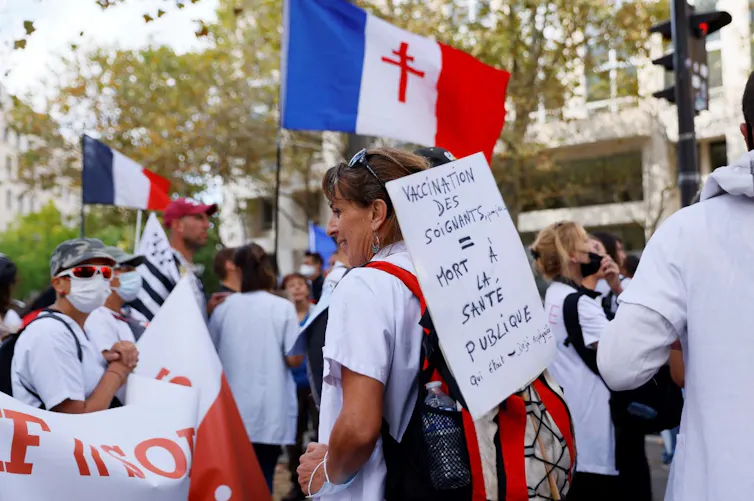 Défilé de soignants en blouse blanche et panneau « Vaccination des soignants = mort à la santé publique »
